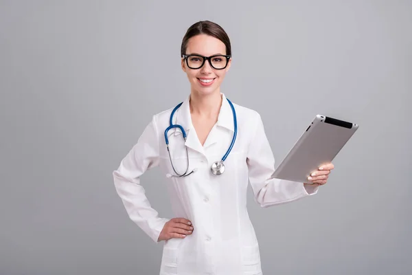 Fotoporträt junge Krankenschwester mit sthethoscope lächelnd mit Tablette bei der Arbeit isoliert graue Farbe Hintergrund — Stockfoto