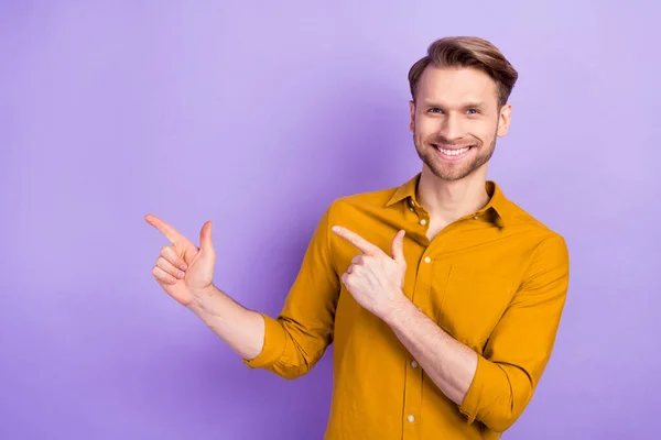 Foto av positiv man toothy leende indikerar fingrar tomt utrymme proposition isolerad på violett färg bakgrund — Stockfoto