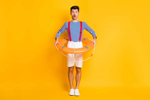 Lunghezza completa foto di stupito bruna uomo tenere bagnino cerchio indossare estate marinaio vestito isolato su sfondo di colore giallo — Foto Stock