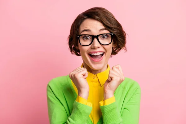 Foto de sorte animado jovem mulher desgaste verde cardigan óculos boca aberta levantando punhos isolado pastel cor rosa fundo — Fotografia de Stock