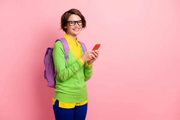 Foto de menina bonito vestido amarelo camisa óculos mochila segurando moderno dispositivo vazio espaço isolado cor rosa fundo — Fotografia de Stock