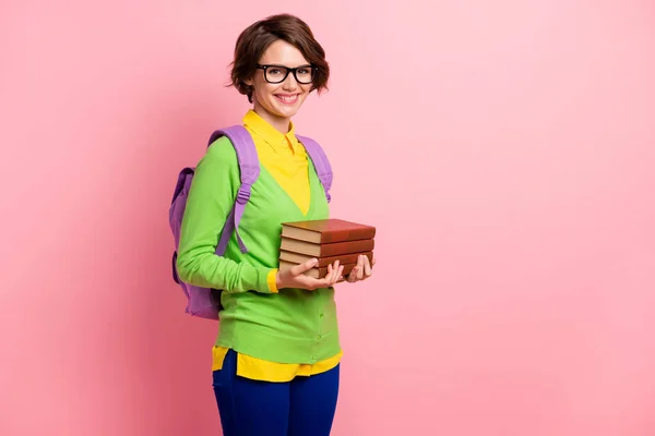 Fotografie sladké mladé dámy oblečené žlutá košile brýle batoh držení knihy zásobník prázdný prostor izolované růžové barvy pozadí — Stock fotografie