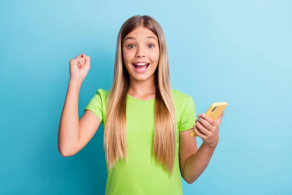 Photo of young happy excited cheerful positive good mood girl hold phone raise fist in victory isolated on blue color background — Stock Photo, Image