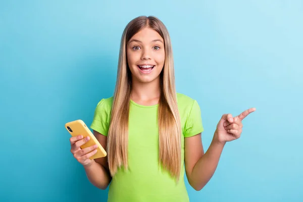 Kuva nuorten iloinen positiivinen hyvällä tuulella hymyilevä tyttö osoittaa sormella copyspace pidä puhelin eristetty sininen väri tausta — kuvapankkivalokuva