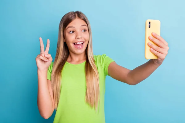 Photo of young pretty lovely charming positive smiling girl taking selfie on phone show v-sign isolated on blue color background — Foto de Stock