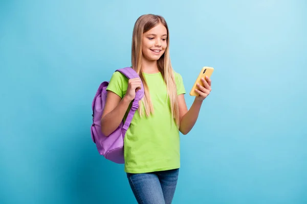 Foto de jovem feliz sorrindo alegre menina positiva vestindo mochila roxa usando telefone isolado no fundo de cor azul — Fotografia de Stock