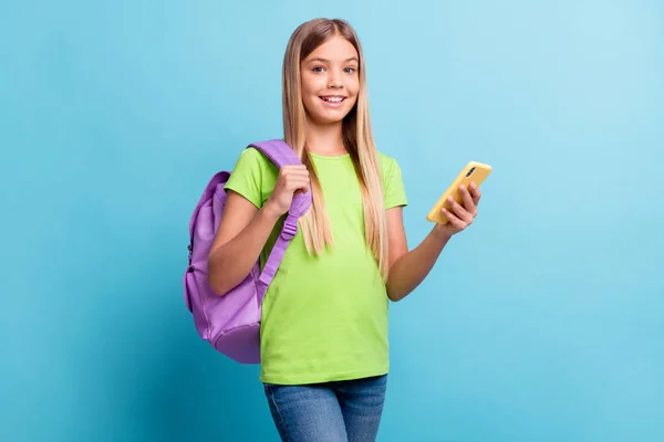 Foto di giovane sorridente allegro buon umore positivo ragazza blogger utilizzando telefono usura borsa viola isolato su sfondo di colore blu — Foto Stock
