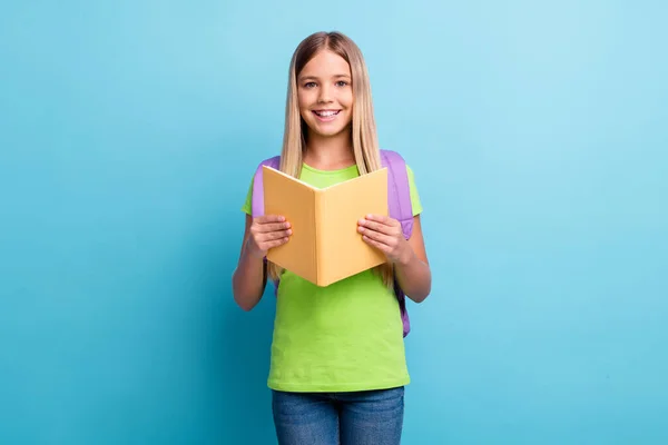 Foto de jovens felizes positivo bom humor menina reding livro desgaste roxo mochila isolada no fundo de cor azul — Fotografia de Stock