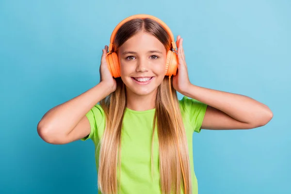 Foto von jungen fröhlich positive gute Laune lächelnde Mädchen mit orangefarbenen Kopfhörern hören Musik isoliert auf blauem Hintergrund — Stockfoto