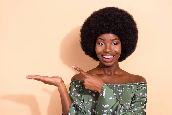 Φωτογραφία της νεαρής μαύρης γυναίκας ευτυχής θετικό χαμόγελο σημείο δάχτυλο promo συμβουλές επιλογής προϊόντος απομονώνονται σε μπεζ φόντο χρώμα — Φωτογραφία Αρχείου
