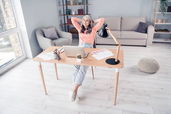 Pleine longueur photo de heureux rêve charmant vieille femme regarder fenêtre relax pause sourire assis table à l'intérieur de la maison — Photo