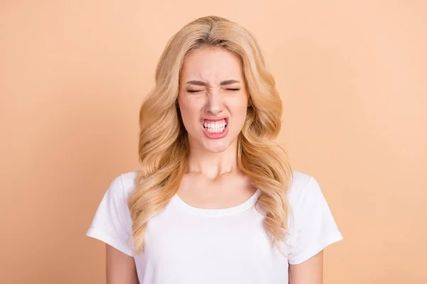 Φωτογραφία από δυστυχισμένη θυμωμένη νεαρή γυναίκα ντυμένη λευκό t-shirt που δείχνει τα δόντια κλειστά μάτια απομονωμένο μπεζ φόντο χρώμα — Φωτογραφία Αρχείου