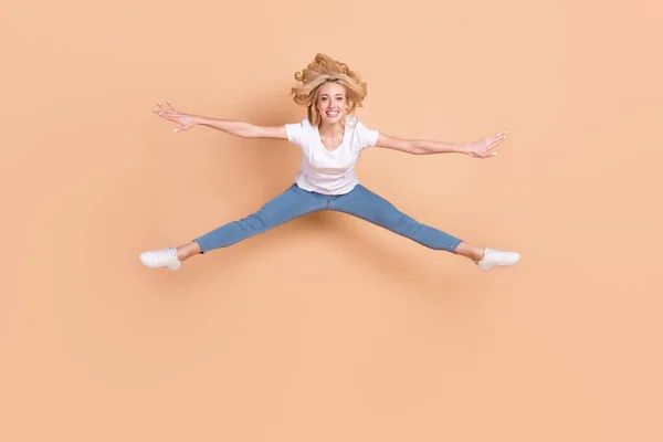 Foto de bonito adorável jovem senhora desgaste branco t-shirt sorrindo salto alto isolado cor bege fundo — Fotografia de Stock