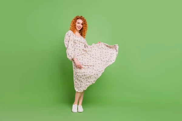 Full length photo of cheerful young happy lady good mood fly wind skirt isolated on green shine color background