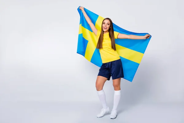 Foto de larga duración de la alegre chica fan del fútbol sostienen bandera sueca apoyar a su equipo nacional en el torneo de la Copa del Mundo desgaste uniforme de fútbol aislado sobre fondo de color gris —  Fotos de Stock