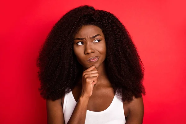 Foto de una joven africana infeliz mano mal toque barbilla pensar mirada espacio vacío aislado sobre fondo de color rojo —  Fotos de Stock