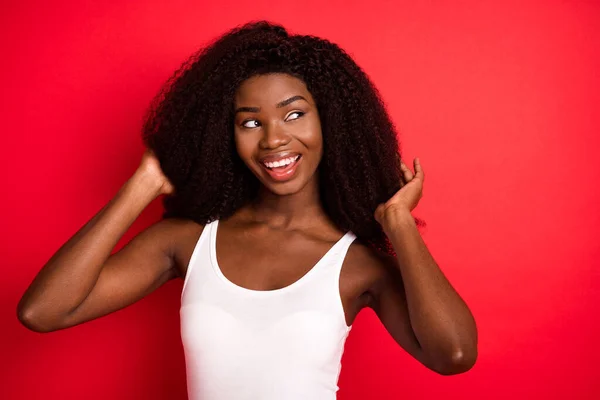 Foto van jong zwart meisje gelukkig positieve glimlach hand aanraken haar genieten haarverzorging shampoo geïsoleerd over rode kleur achtergrond — Stockfoto
