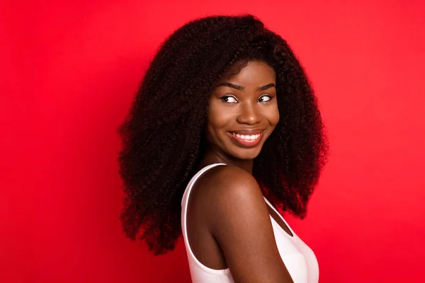 Foto del lado del perfil de la joven alegre chica negra sonrisa positiva feliz mirada espacio vacío aislado sobre fondo de color rojo — Foto de Stock