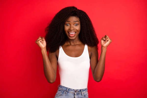 Foto av ung afrikansk flicka glad positiv leende glädje seger nävar händerna isolerade över röd färg bakgrund — Stockfoto