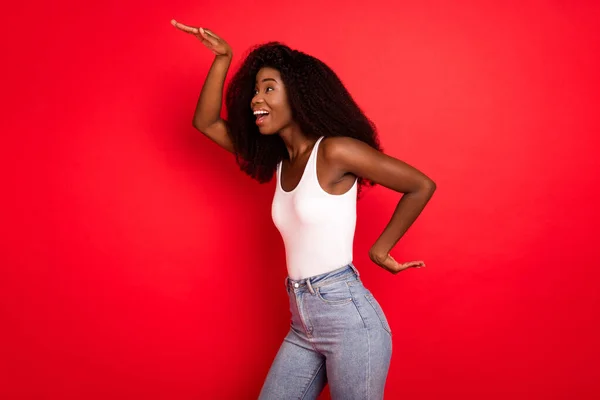 Προφίλ πλευρά φωτογραφία του νεαρού ενθουσιασμένοι αφρικανικό κορίτσι ευτυχισμένο χαμόγελο έχουν διασκέδαση χορό παιχνιδιάρικο απομονωμένο πάνω από το κόκκινο χρώμα φόντο — Φωτογραφία Αρχείου