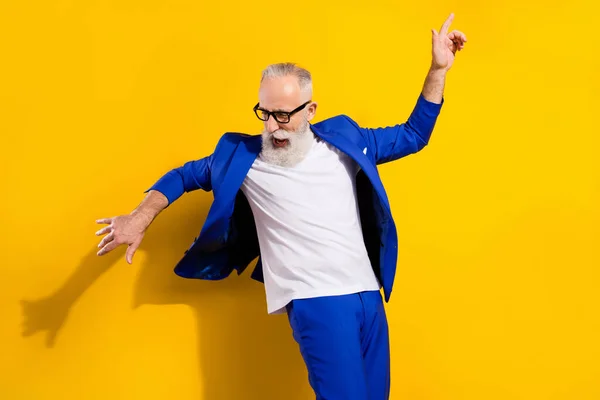 Foto retrato de hombre mayor en traje azul bailando en fiesta aislado color amarillo brillante fondo —  Fotos de Stock