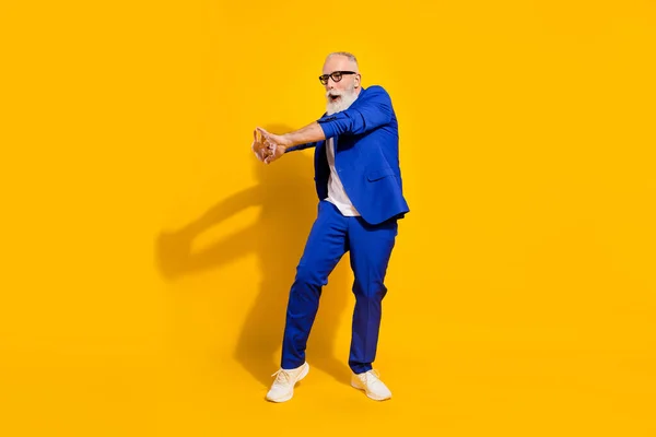 Foto de perfil de tamaño completo de la barba gris funky hombre viejo danza gafas chaqueta azul aislado sobre fondo amarillo —  Fotos de Stock