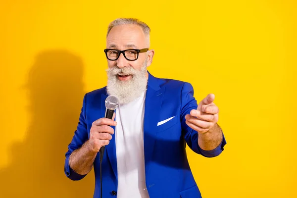 Photo portrait of cool man wearing blue suit glasses smiling talking in microphone singing isolated vivid yellow color background — Stock Photo, Image