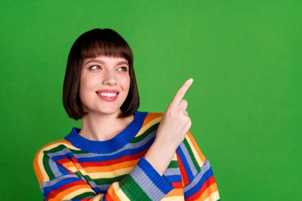 Фото позитивной счастливой молодой женщины указывать пальцем пустое пространство смотреть улыбку изолированы на зеленом фоне — стоковое фото