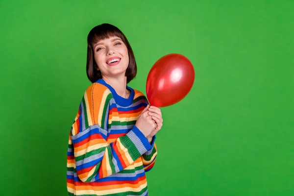 Foto de atractiva joven sonrisa buen humor cogido de la mano globo rojo aislado sobre fondo de color verde — Foto de Stock