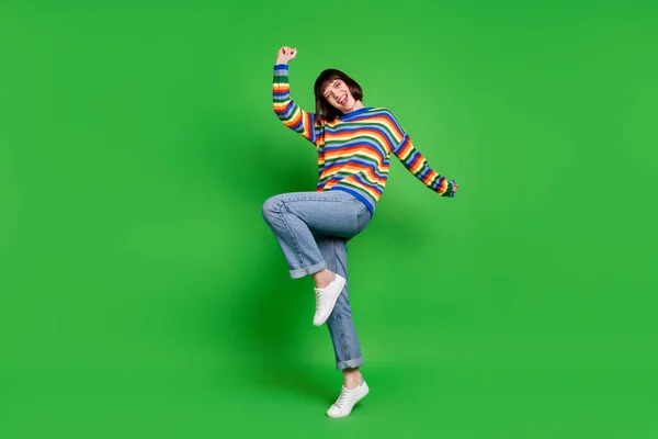Foto de comprimento total de adorável sorte jovem mulher desgaste listrado suéter sorrindo crescente punhos isolado cor verde fundo — Fotografia de Stock