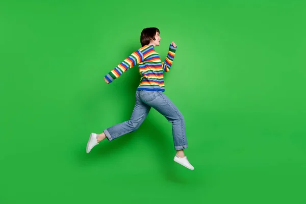Foto de comprimento total de doce mulher bonita usar camisola listrada sorrindo saltar correndo espaço vazio isolado cor verde fundo — Fotografia de Stock