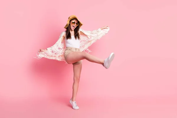 Фотографія повного розміру безтурботної позитивної леді, що піднімає ногу відкритими руками, тримає кардиган ізольовано на рожевому кольоровому фоні — стокове фото