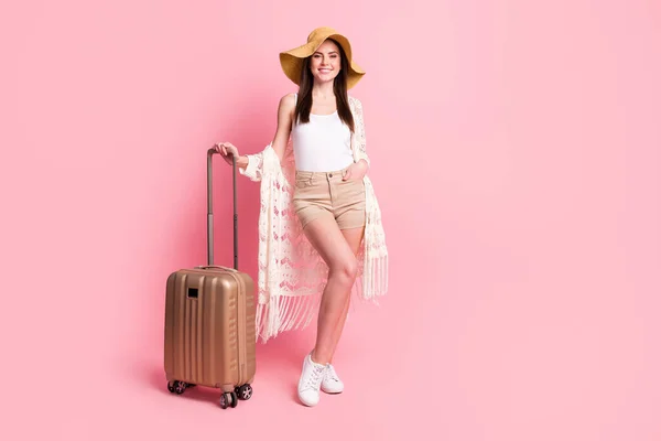 Foto de linda mujer dulce vestida de cárdigan blanco headwear sonriendo sosteniendo maleta espacio vacío aislado color rosa fondo —  Fotos de Stock