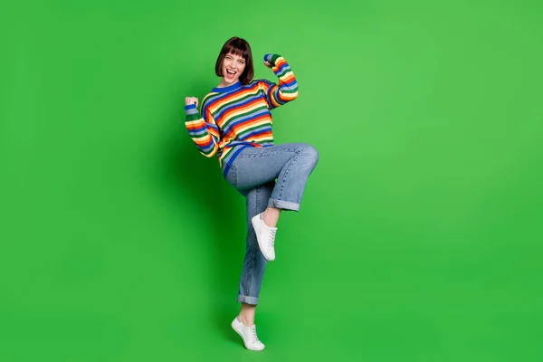 Foto de comprimento total de sorte brilhante jovem senhora vestida pulôver colorido crescente punhos sorrindo isolado cor verde fundo — Fotografia de Stock