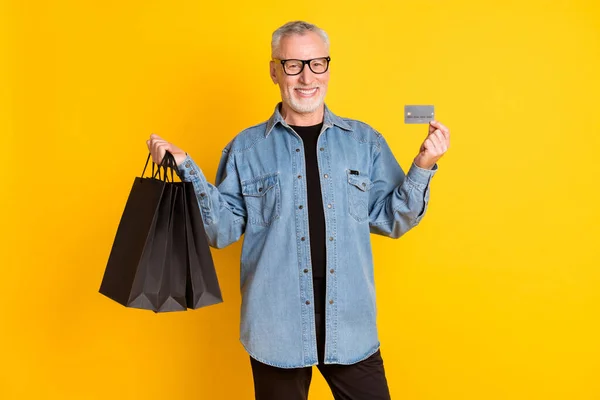 Photo of funny grandpa stand with bags card do shopping wear jacket isolated on yellow color background — 图库照片