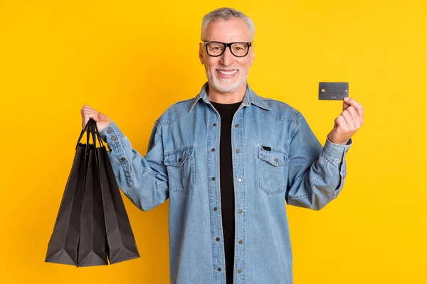 Foto von funky Opa stehen mit Taschen Karte tun Einkaufsbekleidung Jacke isoliert auf gelbem Hintergrund — Stockfoto