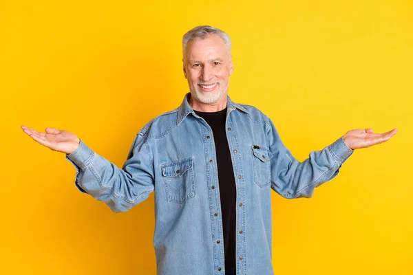 Photo of trend feel young grandpa hold empty space wear jeans jacket isolated on vivid yellow color background — Stockfoto
