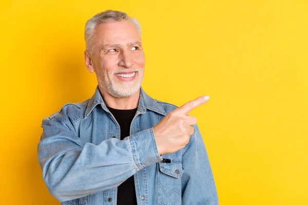 Photo of funky senior granddad point look empty space wear jeans jacket isolated on vivid yellow color background — ストック写真
