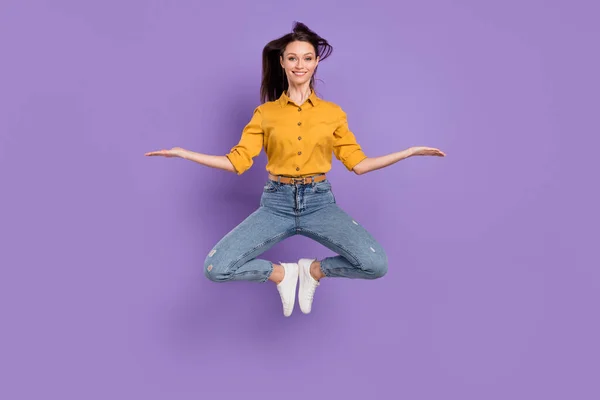 Full length body size photo jumping high girl smiling comparing blank spaces on hands isolated pastel purple color background — Stockfoto