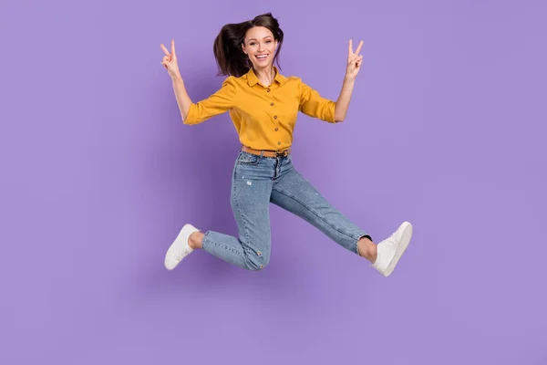 Volledige lengte lichaam grootte foto springen meisje glimlachen dolblij tonen v-teken geïsoleerde pastel paarse kleur achtergrond — Stockfoto