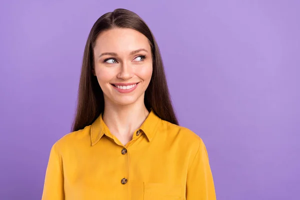 Foto retrato de la mujer sonriendo usando camisa amarilla buscando espacio en blanco aislado sobre fondo de color violeta pastel —  Fotos de Stock