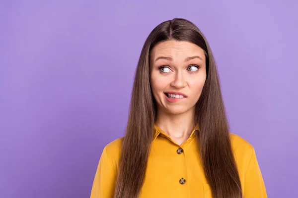 Photo of sad young lady bite lips look empty space wear yellow shirt isolated on vivid violet color background — Stok fotoğraf