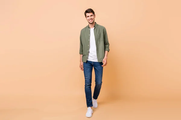 Photo of attractive charming young guy dressed green shirt smiling walking isolated beige color background — Stok fotoğraf