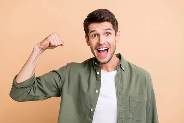 Photo of happy positive young man raise fist smile amazed winner success isolated on beige color background — Stok fotoğraf