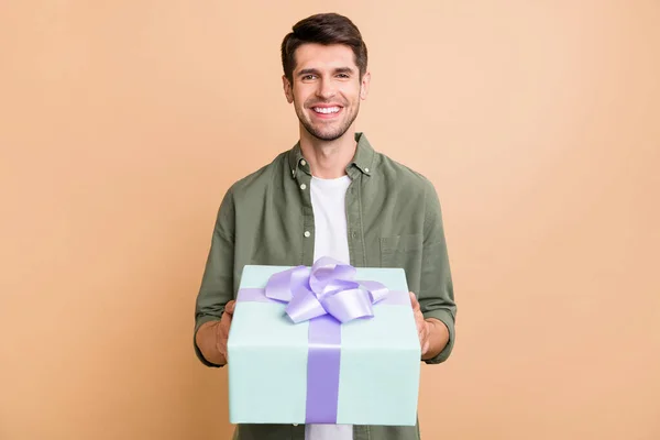 Foto de encantador jovem feliz dar caixa de presente que você sorri comemorar feriado isolado no fundo de cor bege — Fotografia de Stock