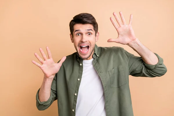 Photo of amazed shocked young man raise hands surprised news isolated on pastel beige color background — 스톡 사진