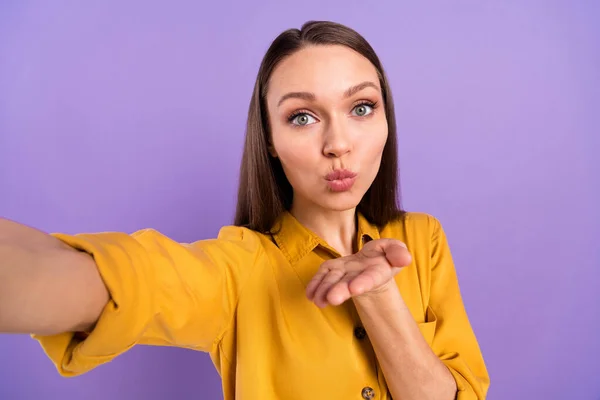 Portrait photo d'une femme souriante qui envoie un baiser d'air en prenant un selfie isolé sur un fond violet pastel — Photo