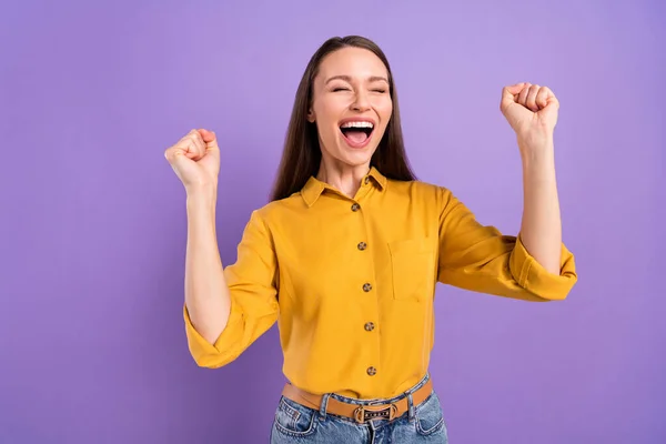 Foto de surpreendido jovem senhora mãos punhos gritar usar camisa amarela isolada no fundo de cor violeta vívida — Fotografia de Stock