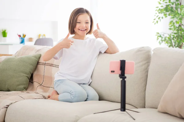 Foto corpo pieno di giovane bambina felice sorriso positivo parlare video chiamata cellulare spettacolo pollice in su cool scelta fine sedersi divano al chiuso — Foto Stock