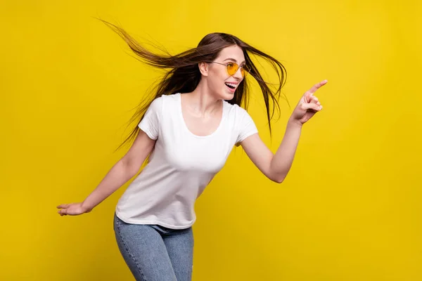 Profilo foto laterale di giovane ragazza felice sorriso positivo guardare punto dito vuoto spazio volare aria capelli isolati su sfondo di colore giallo — Foto Stock